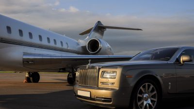 : Private executive airplane with limousine Rolls Royce Phantom luxury car shown together at international Heathrow Airport. VIP service at the airport. Business-class transfer