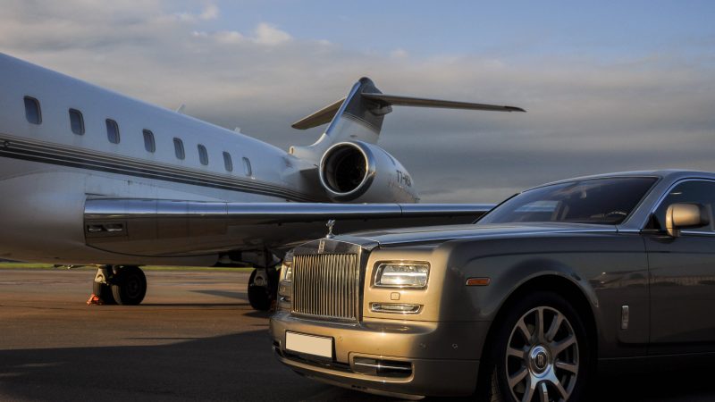 : Private executive airplane with limousine Rolls Royce Phantom luxury car shown together at international Heathrow Airport. VIP service at the airport. Business-class transfer