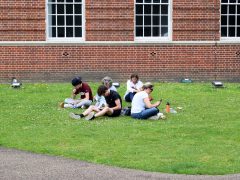 London, UK - Jul 15, 2024: Students and their parents check smartphones on the campus lawn