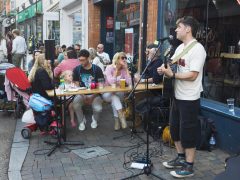 Musician plays as family watch outside a pub