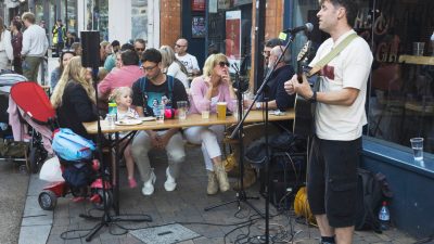 Musician plays as family watch outside a pub
