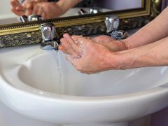 Hands being washed under taps.