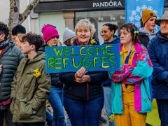 Woman holding sign saying welcome refugees