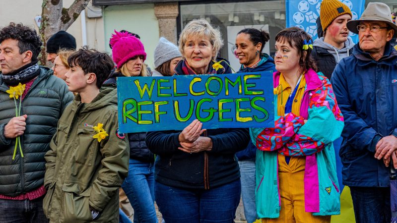 Woman holding sign saying welcome refugees