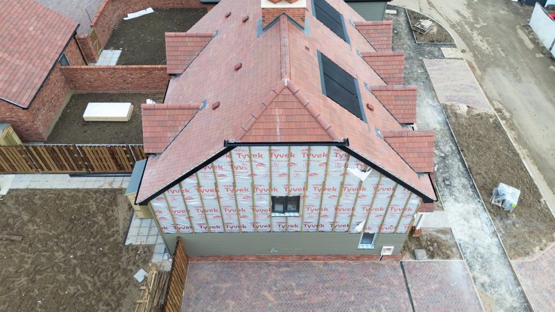 Drone view of a near completed semi detached first time buyer property within a new housing estate. The house insulation is currently exposed, soon to be covered