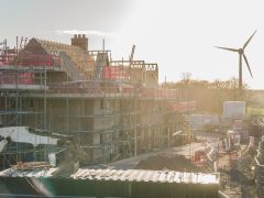 House under construction with wind turbine renewable energy