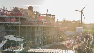House under construction with wind turbine renewable energy