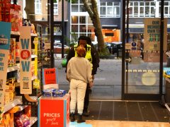 Security guard questions a regular female shoplifter carrying a bag of unpaid food