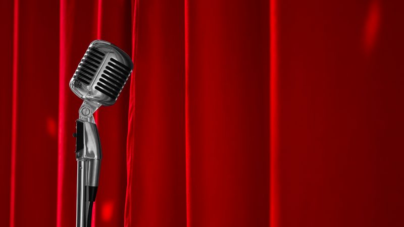 Old fashioned mic in front of red curtain for stand up