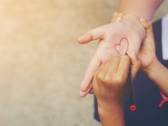 Child draws heart on adult's open hand