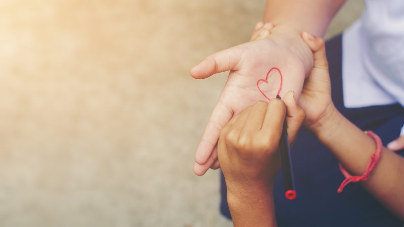 Child draws heart on adult's open hand