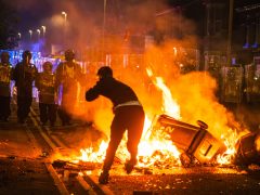 A rioter throws a brick at police during riots in Southport.