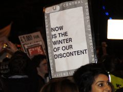 Woman holding sign saying "Now is the winter of our discontent"
