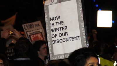 Woman holding sign saying "Now is the winter of our discontent"