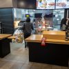 Interior of a fast food retailer showing workers behind the counter.