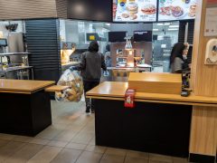 Interior of a fast food retailer showing workers behind the counter.