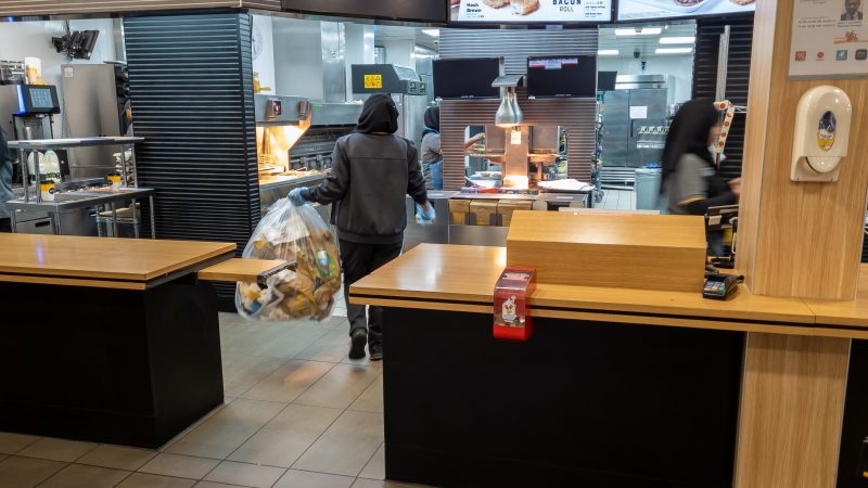 Interior of a fast food retailer showing workers behind the counter.