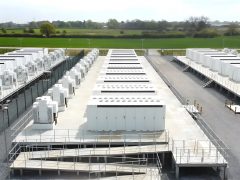 View of a large-scale battery energy storage park featuring multiple rows of battery storage units.